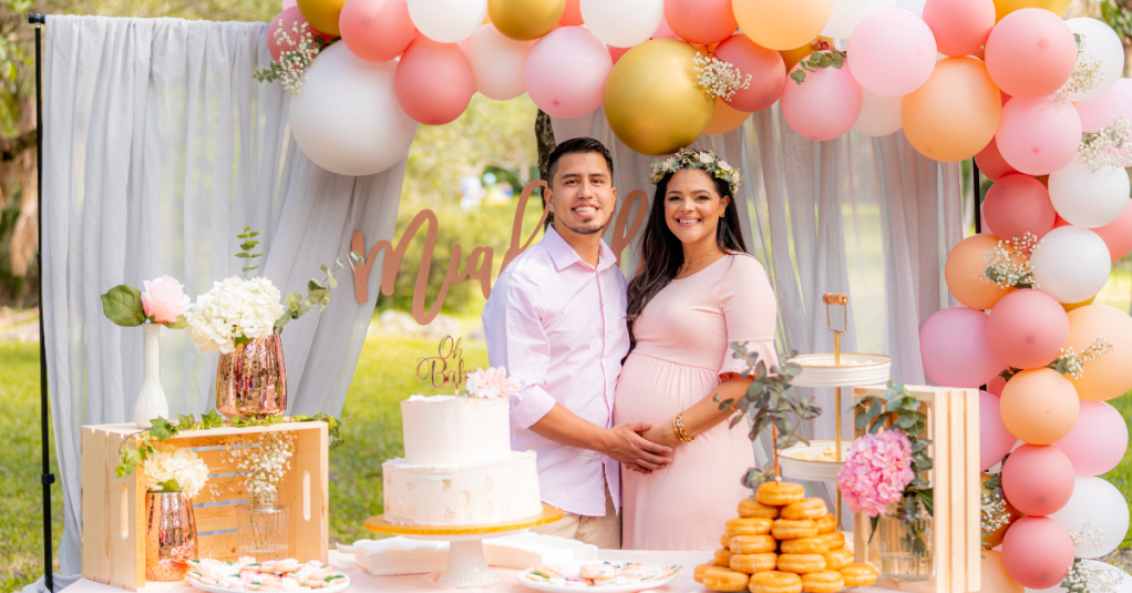 A man and woman, presumably married, at a baby shower the woman is pregnant.