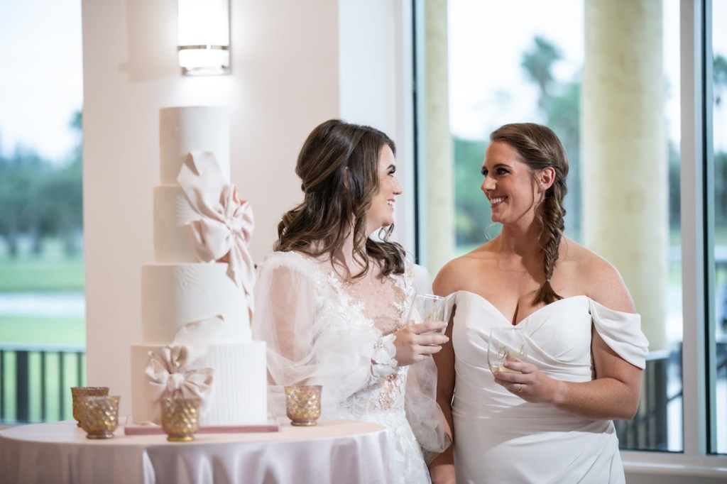 Palm Beach wedding venue reception with two brides and a luxury wedding cake with bows and icing.