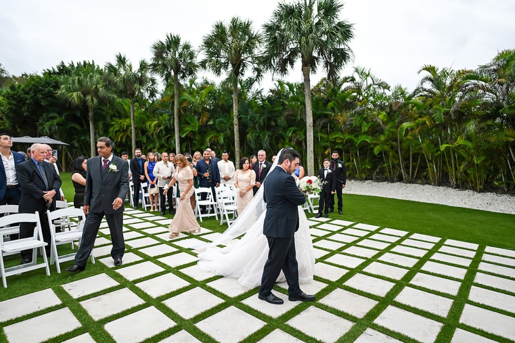Palm Beach Florida outdoor wedding ceremony with waterfront views, palm trees and beautiful landscaping.